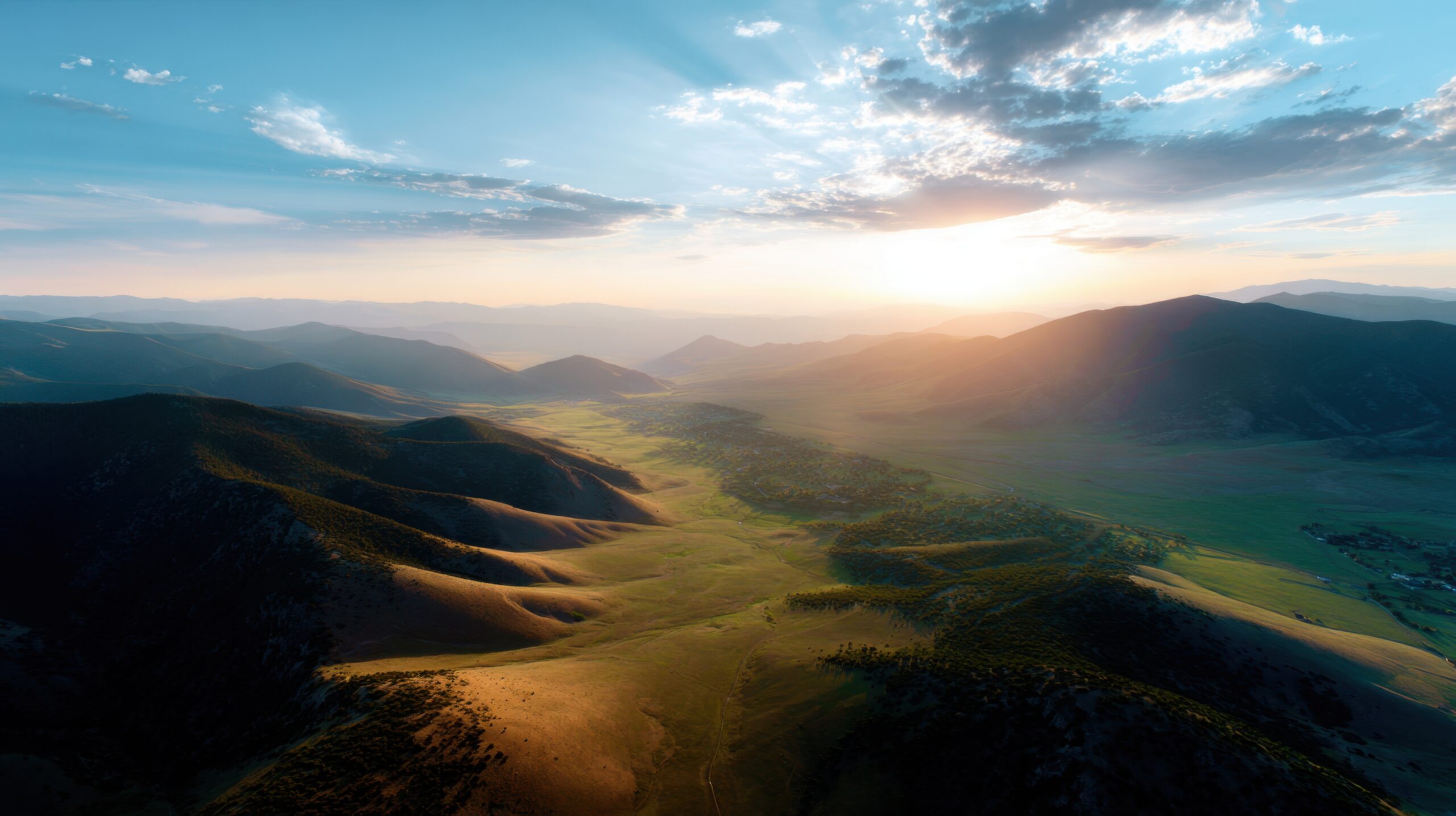 High-altitude aerial of mountain valley at sunset, golden light washing over rolling hills, tranquil and inspiring landscape for meditation or lifestyle stock photo